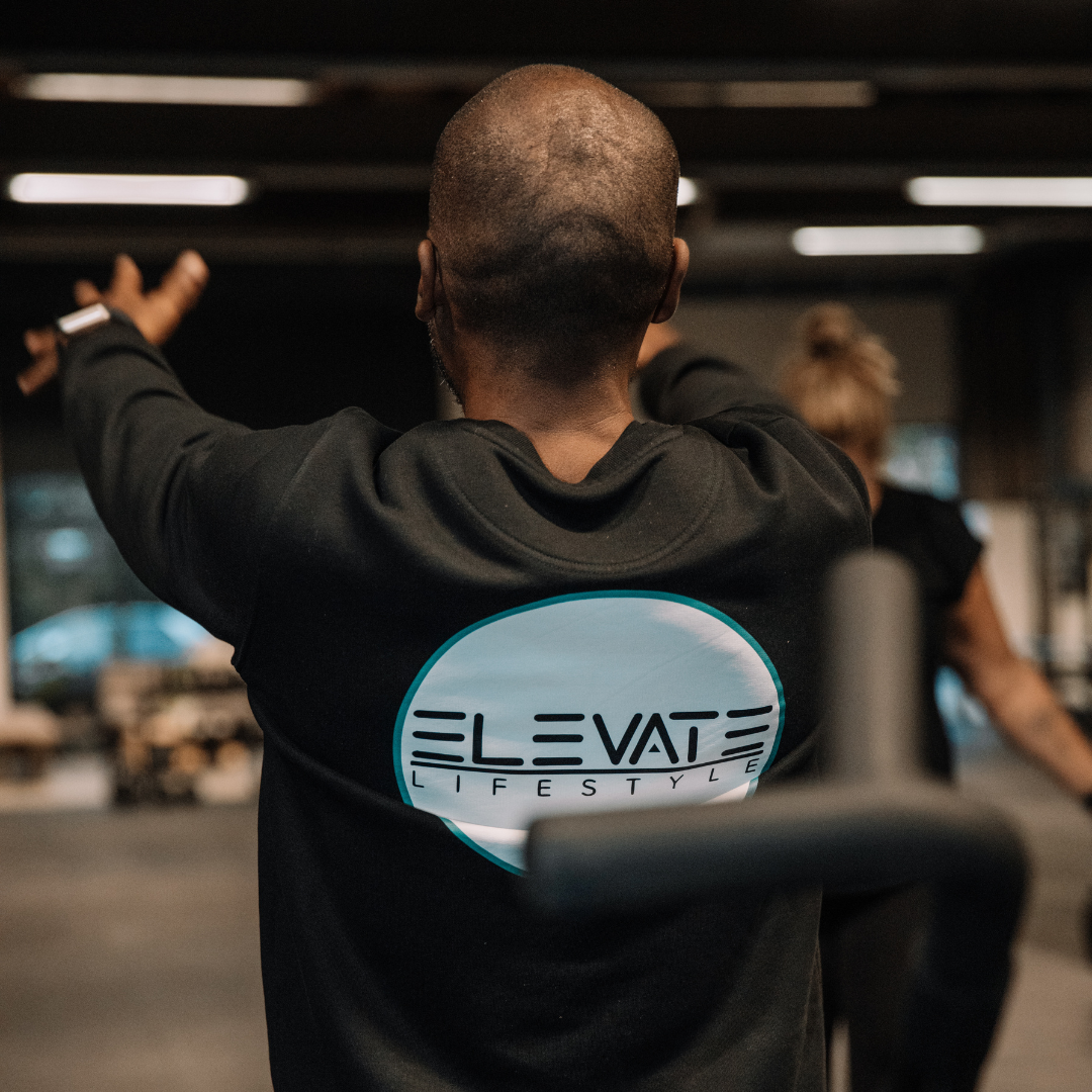 Foto van een man met een trui van Elevate Lifestyle met het logo op de achterkant.