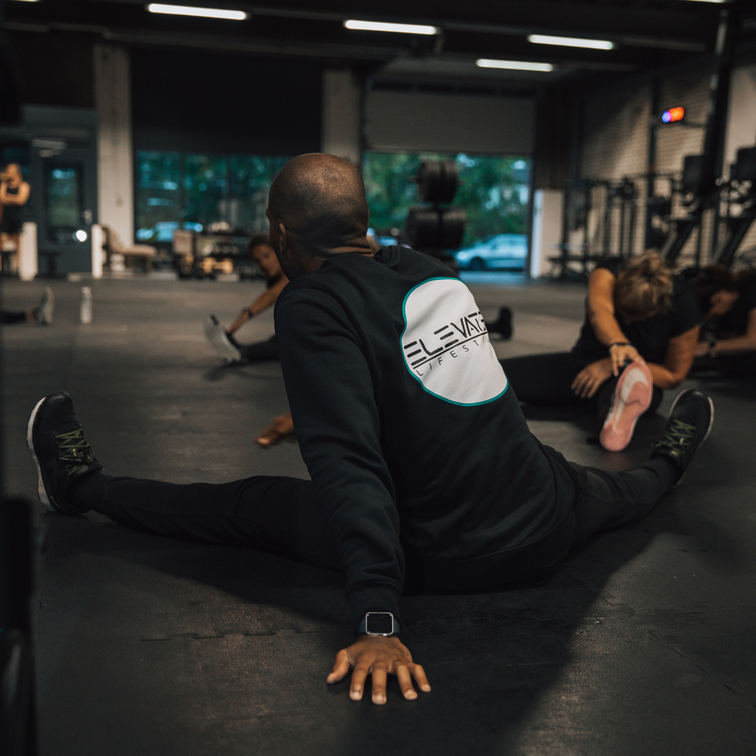 Een lifestylecoach van Elevate die een stretchoefening uitvoert met een groep.